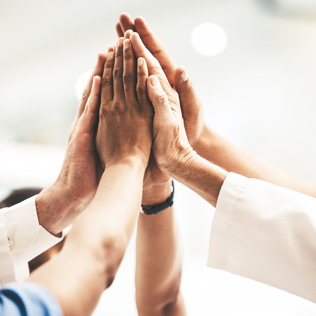 Hände mehrerer Menschen, die Teamwork symbolisieren.